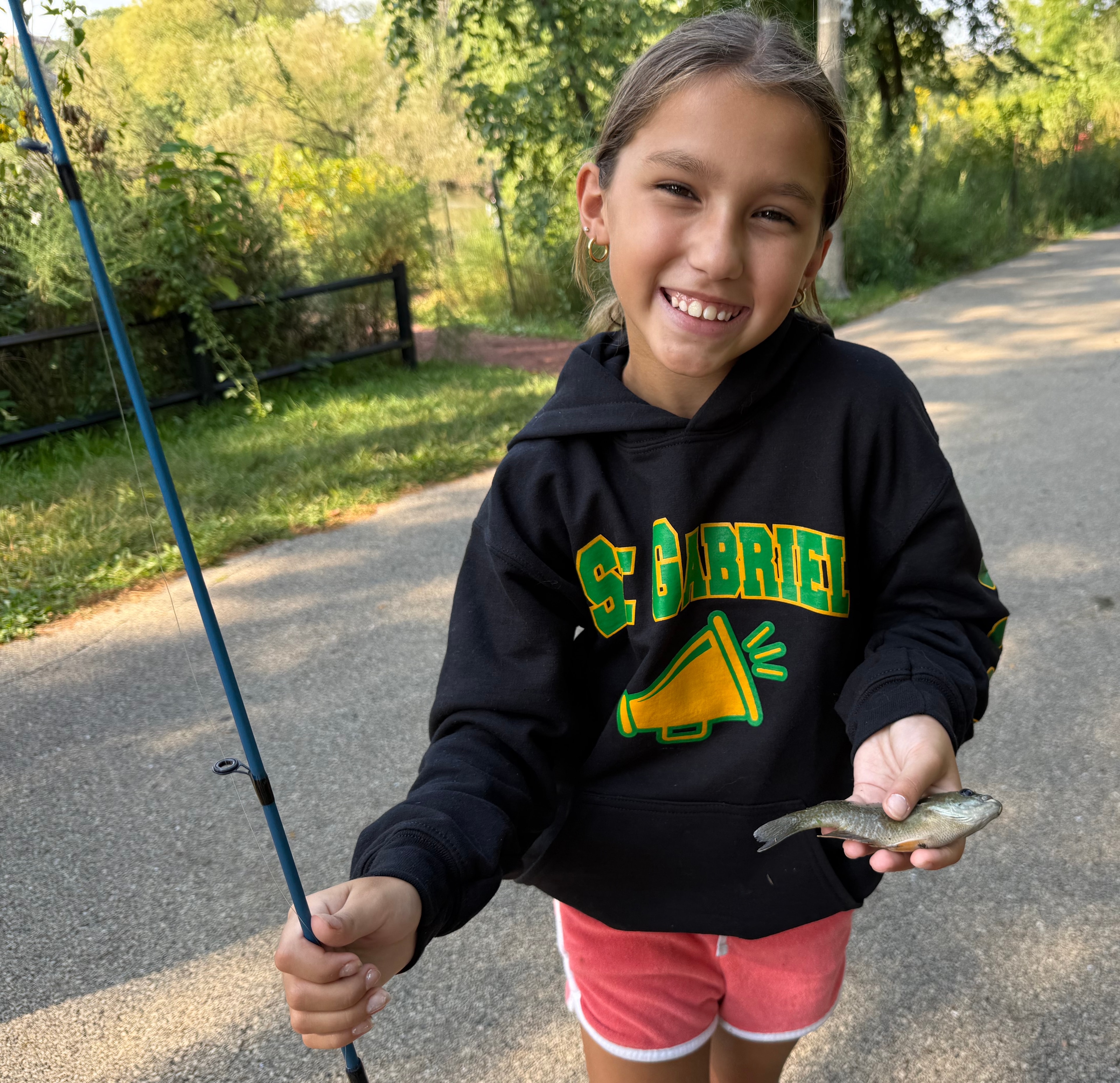 Young girl proudly holding her catch at the fishing derby